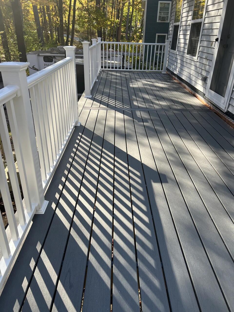 Finished deck with fresh decking and white railings casting afternoon shadows